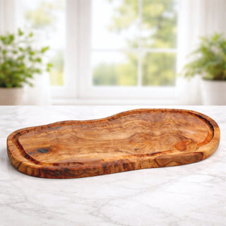 side view of an olive wood carving board for personalized family name engraving on a marble surface with kitchen items perfect for wedding, engagement, and housewarming gift